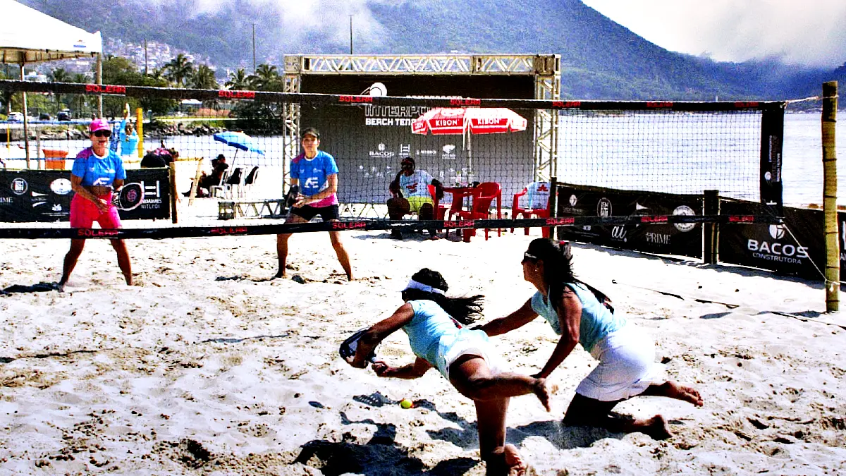 ogadora mergulhando na areia para rebater bola em partida de beach tennis feminino no campeonato Interpoints BT 2025, em Niterói.