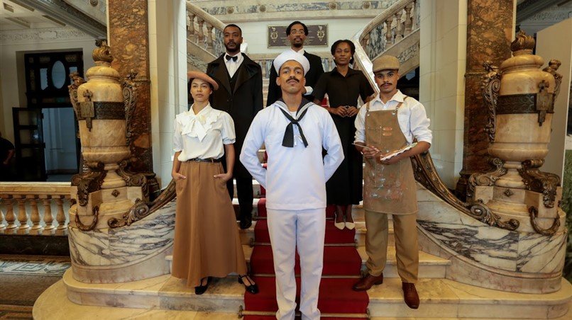 Atores caracterizados posam na escadaria do Palácio: personagens históricos ganham voz na cena e reconstituem episódios centrais da luta negra no Brasil.